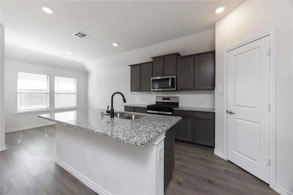 a kitchen with kitchen island granite countertop a stove sink and microwave