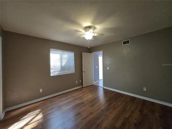 a view of an empty room with window and wooden floor