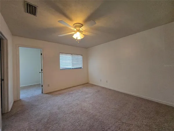 an empty room with a window and a ceiling fan