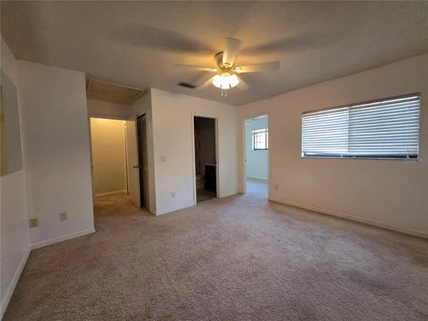 an empty room with windows and fan