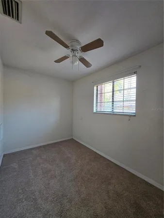 an empty room with a window and a fan