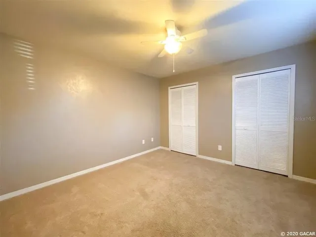 an empty room with a chandelier fan and windows