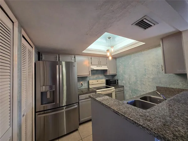 a kitchen with stainless steel appliances granite countertop a refrigerator a sink a stove and island