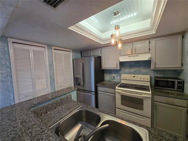 a kitchen with granite countertop a refrigerator and a sink
