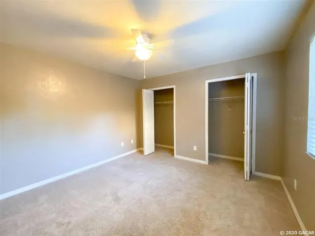 an empty room with closet and a chandelier fan