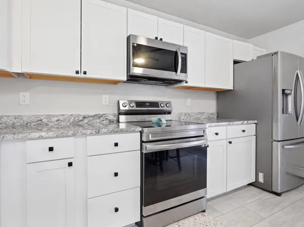 a kitchen with stainless steel appliances granite countertop white cabinets stove a sink and dishwasher