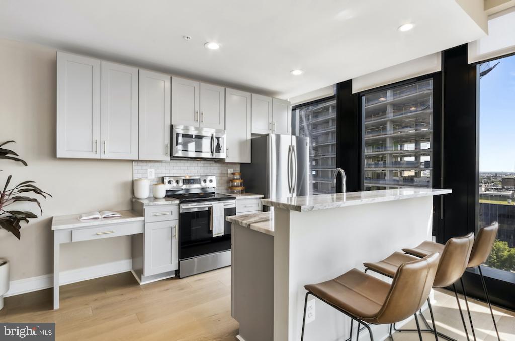 30 North 23rd Street, Unit 1808 Philadelphia, PA 19103 - Photo 12 of 42 a kitchen with stainless steel appliances granite countertop a stove top oven a sink dishwasher and a refrigerator