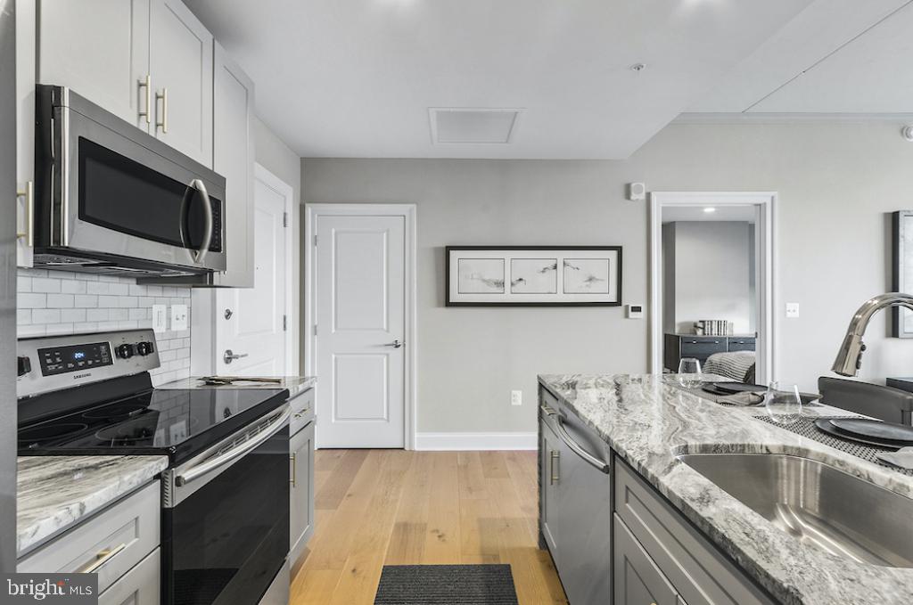 30 North 23rd Street, Unit 1808 Philadelphia, PA 19103 - Photo 13 of 42 a kitchen with granite countertop a sink and steel appliances