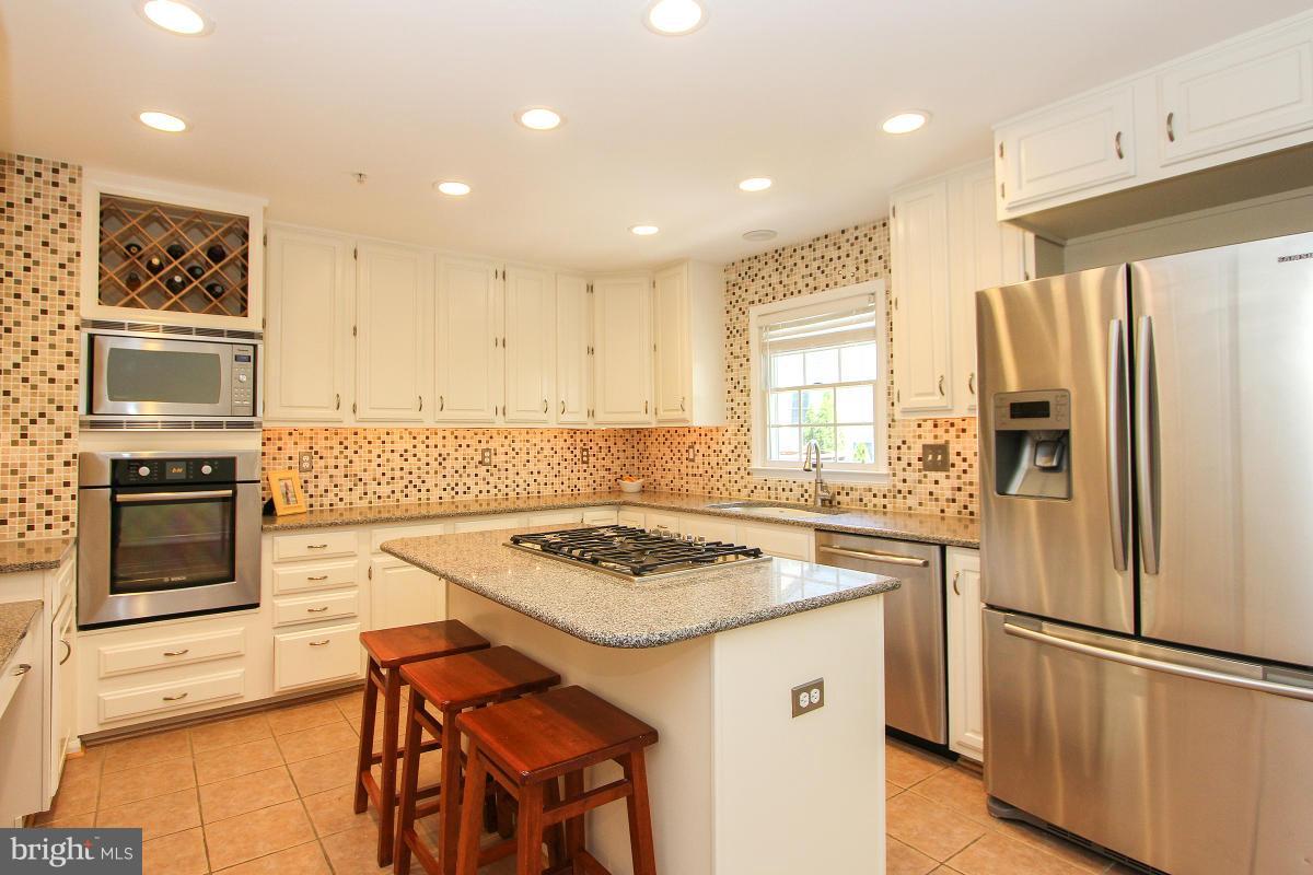12666 Granite Ridge Drive North Potomac, MD 20878 - Photo 13 of 30 a kitchen with stainless steel appliances granite countertop a stove refrigerator sink and microwave