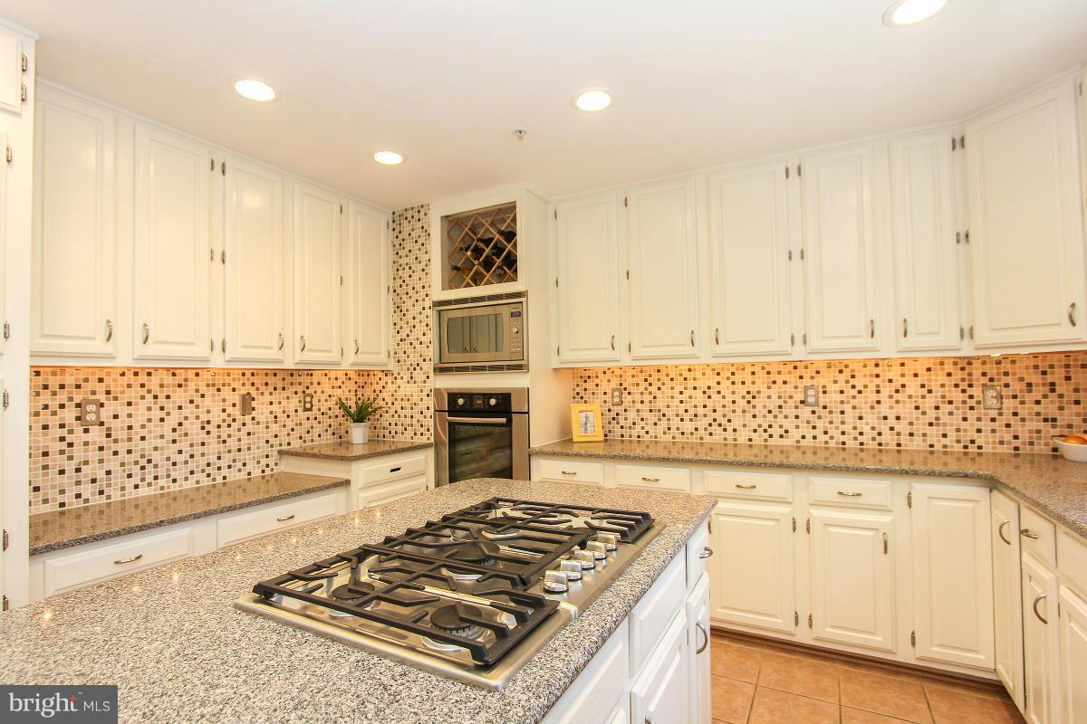 12666 Granite Ridge Drive North Potomac, MD 20878 - Photo 17 of 30 a kitchen with granite countertop a stove top oven microwave and cabinets