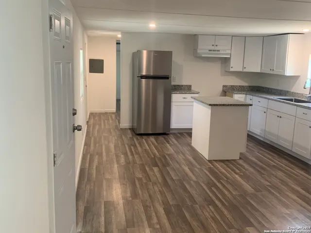 a kitchen with a refrigerator and white cabinets