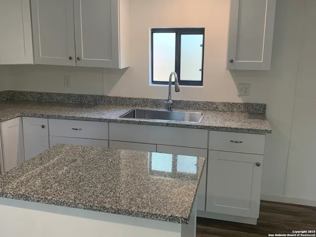 a kitchen with granite countertop a sink and white cabinets