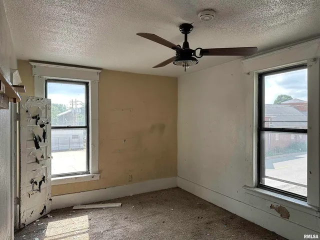 a view of empty room with windows and ceiling fan