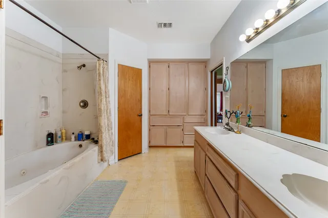 a bathroom with a tub a sink and a large mirror