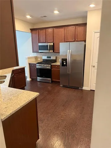 a kitchen with stainless steel appliances granite countertop a refrigerator stove microwave and sink