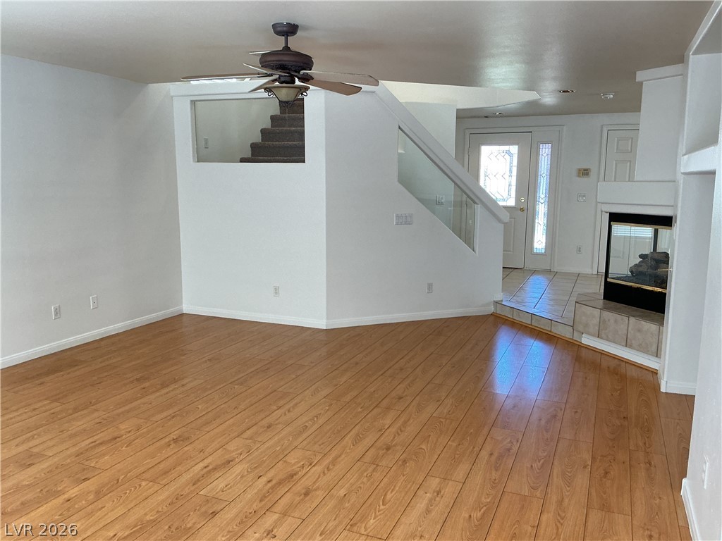 10975 Calcedonian Street Las Vegas, NV 89141 - Photo 10 of 25 This inviting living area boasts rich wood flooring and a cozy fireplace, creating a warm and welcoming ambiance.
