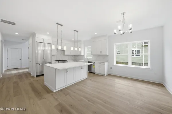 a large white kitchen with kitchen island a sink a center island stainless steel appliances and a cabinets