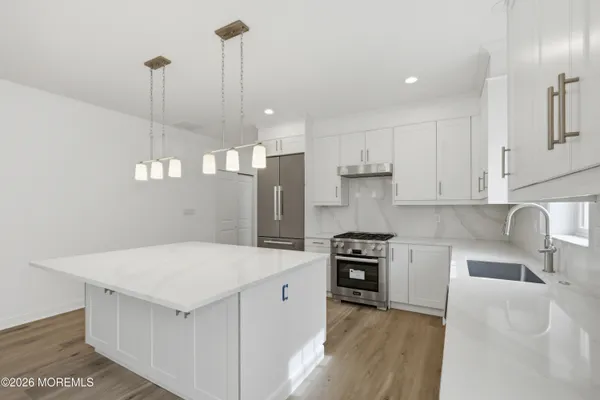 a kitchen with a stove a sink a refrigerator and chairs