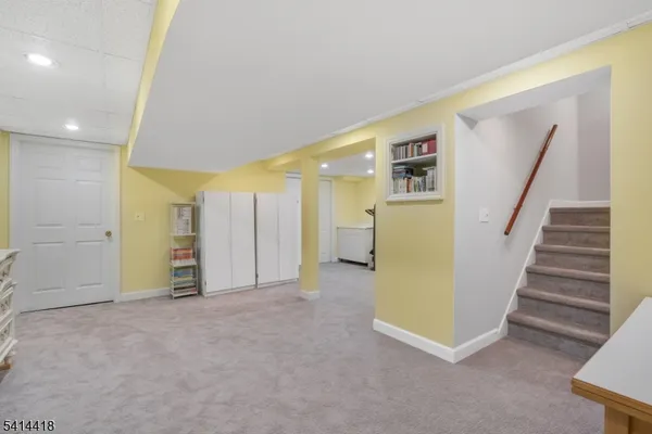 a view of an empty room with stairs and a kitchen
