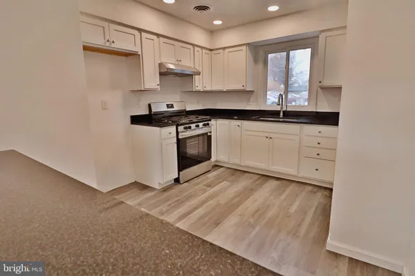 a kitchen with stainless steel appliances white cabinets a sink and a stove