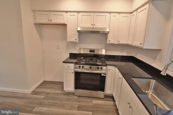 a kitchen with granite countertop a stove sink and cabinets
