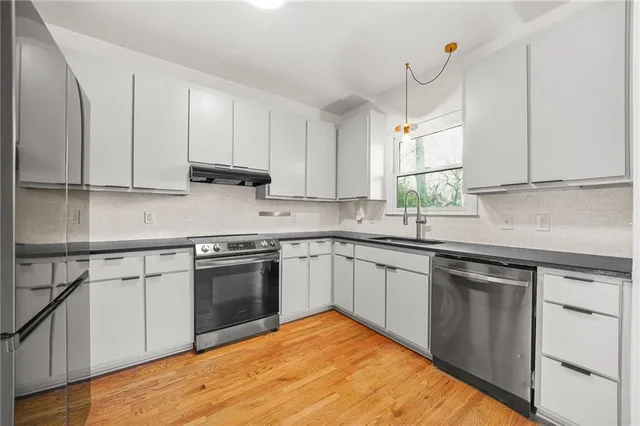 a kitchen with stainless steel appliances granite countertop a sink stove and cabinets