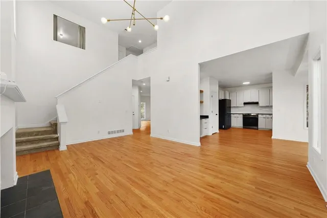 a view of an empty room with wooden floor kitchen view and a window