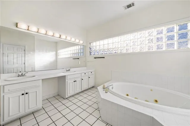 a bathroom with a bathtub a double vanity sink and mirror