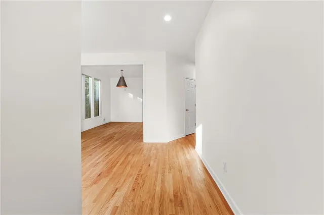 a view of a hallway with wooden floor and a bathroom
