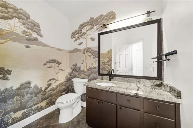 a bathroom with a granite countertop sink mirror vanity and toilet