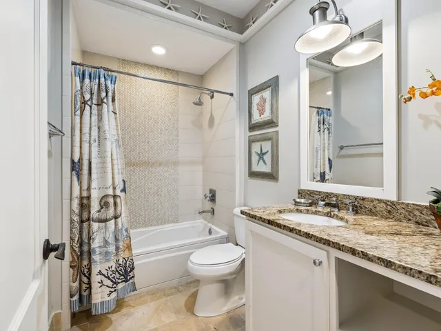 a bathroom with a granite countertop sink a toilet and shower