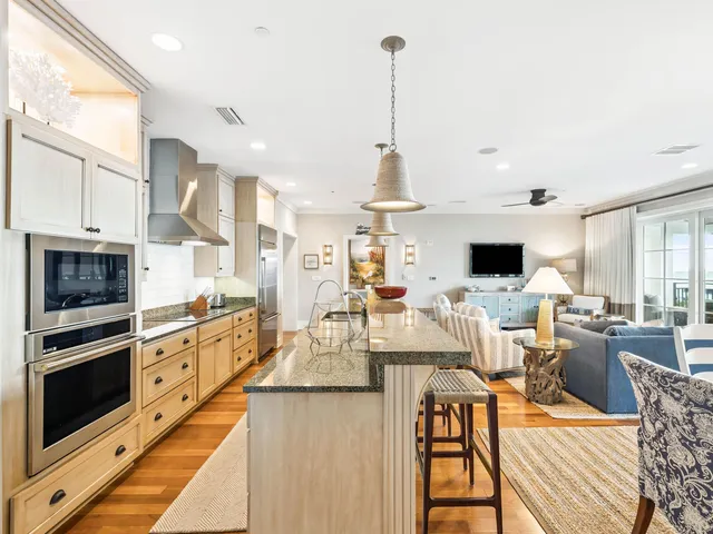 a view of a dining room and livingroom with furniture wooden floor kitchen view and a chandelier