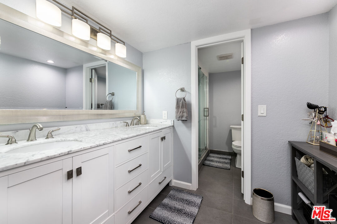 231 Bethany Road, Unit 210 Burbank, CA 91504 - Photo 15 of 22 a spacious bathroom with a granite countertop sink mirror and a toilet