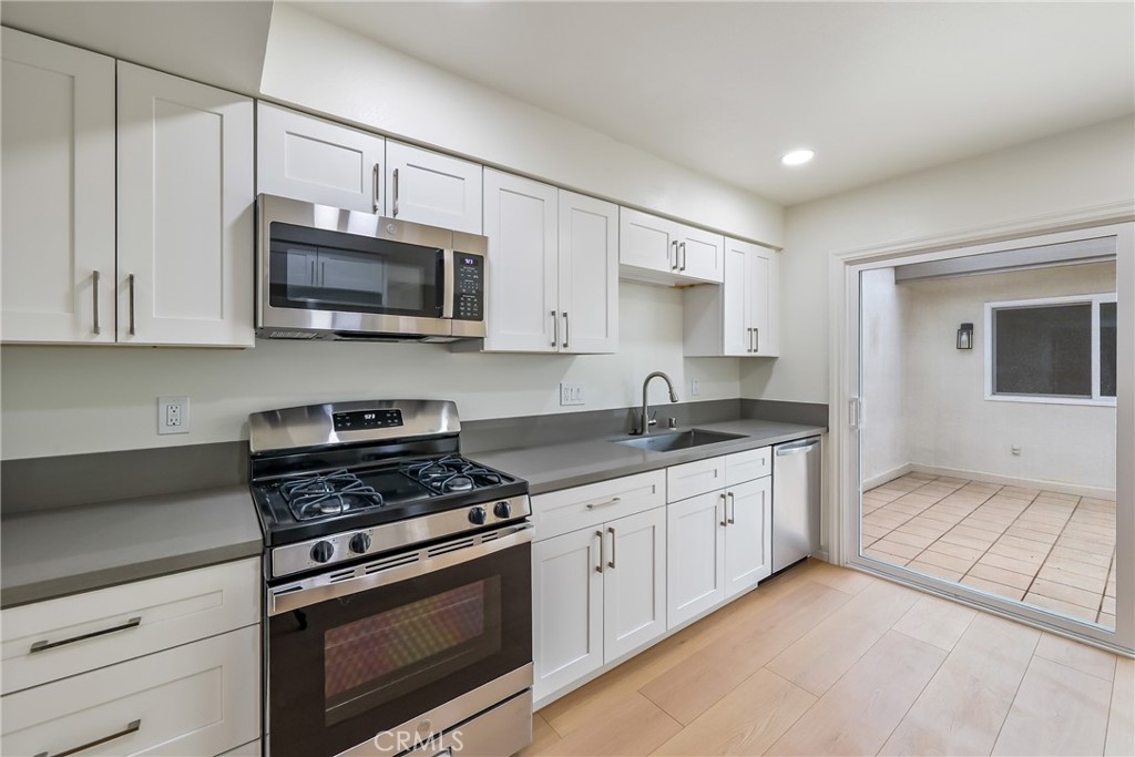 71 Seton Road Irvine, CA 92612 - Photo 5 of 22 a kitchen with granite countertop white cabinets sink and stainless steel appliances