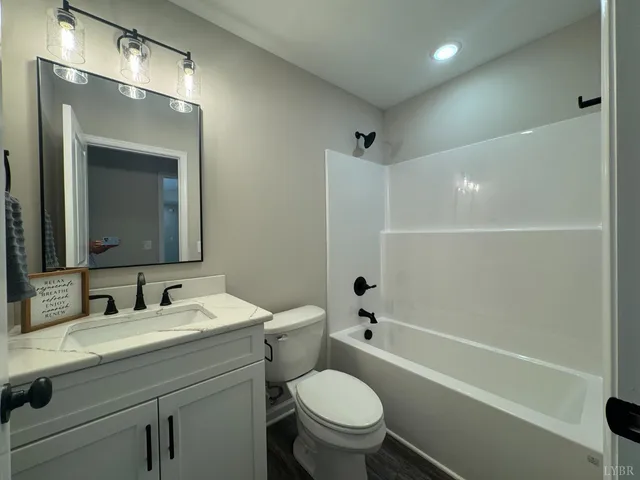 a bathroom with a toilet a sink a mirror a bathtub and vanity
