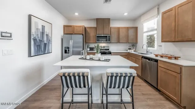 a kitchen with stainless steel appliances granite countertop a sink a stove a refrigerator with a dining table and chairs