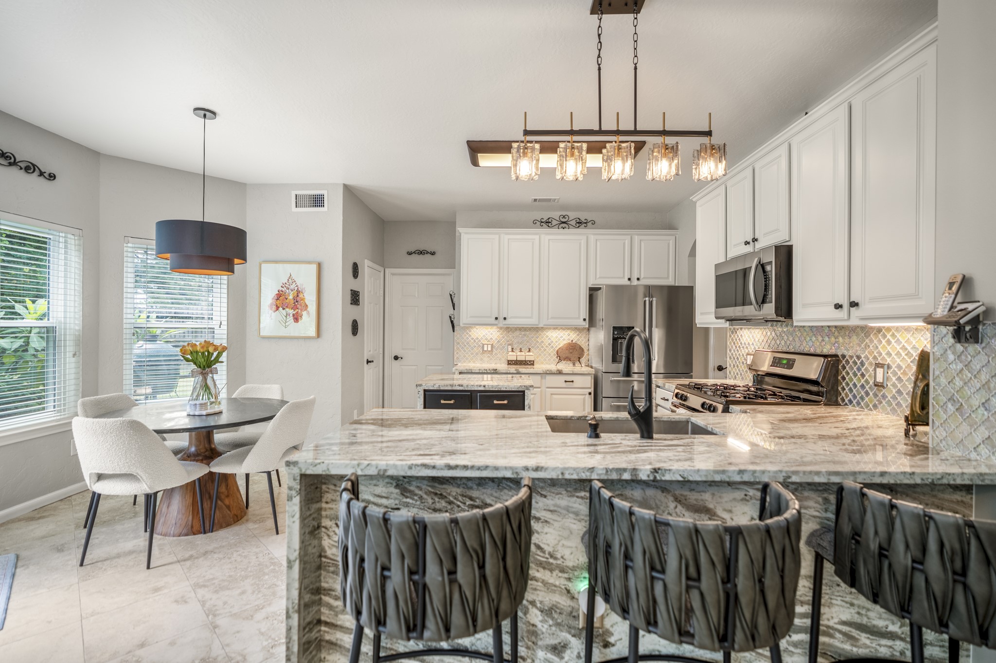 20235 Eden Pines Spring, TX 77379 - Photo 12 of 50 Now the kitchen gets its moment. Bright painted cabinetry is paired with granite that catches the light, a decorative glass backsplash with the shine the sellers love, and a long peninsula that doubles as prep space and a natural gathering spot. The breakfast nook sits just beyond, making it easy to imagine everything from morning coffee to friends lingering around the kitchen during dinner.