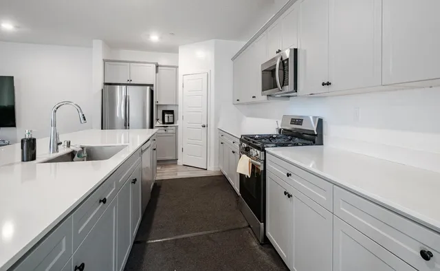 a kitchen with stainless steel appliances a sink stove refrigerator and cabinets