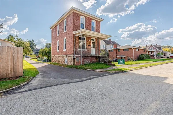 a view of a big house with a big yard and large trees