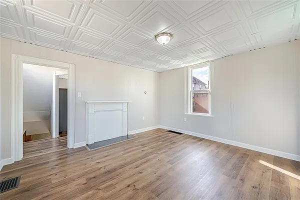 an empty room with wooden floor & windows