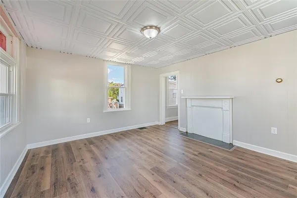 an empty room with wooden floor chandelier and windows