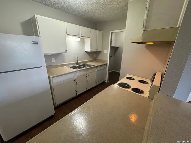 a kitchen with stainless steel appliances a refrigerator a sink a stove and white cabinets