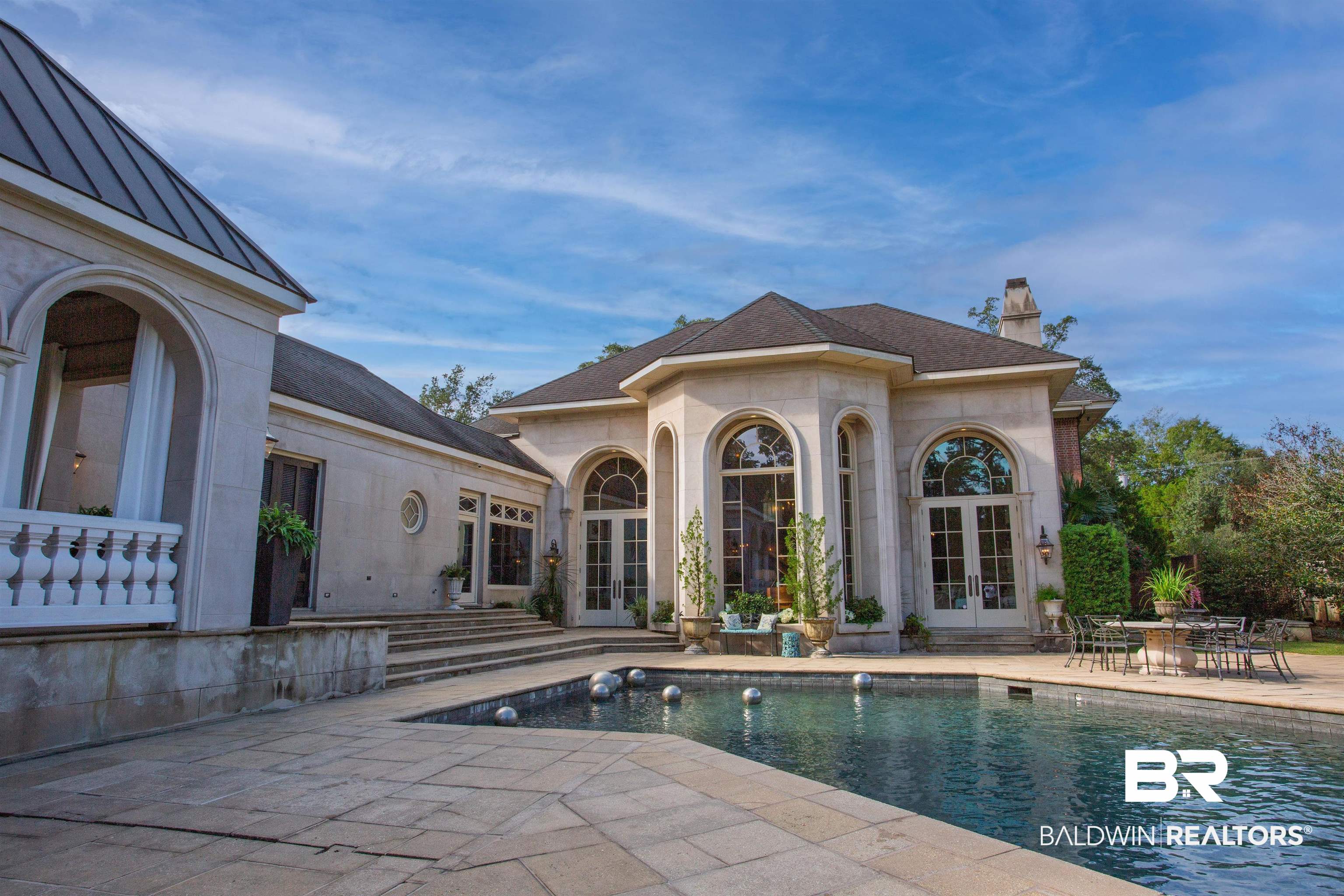 150 Austill Avenue Mobile, AL 36608 - Photo 2 of 39 Exterior featuring a swimming pool, expansive stone patio, and arched windows