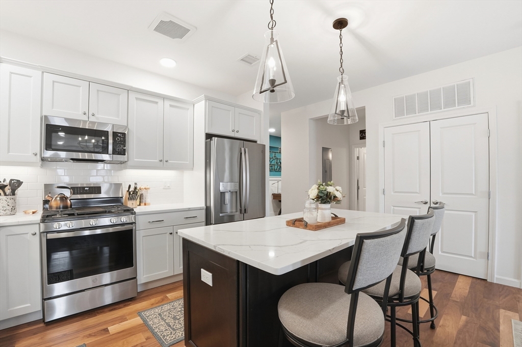 15 Revolution Way, Unit 2205 Canton, MA 02021 - Photo 5 of 34 a kitchen with stainless steel appliances granite countertop a stove a refrigerator a kitchen island a dining table and chairs