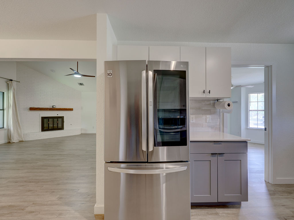 5842 Secrest Drive Austin, TX 78759 - Photo 14 of 40 A sleek stainless steel refrigerator anchors this modern kitchen, blending seamlessly into the open-concept living space.