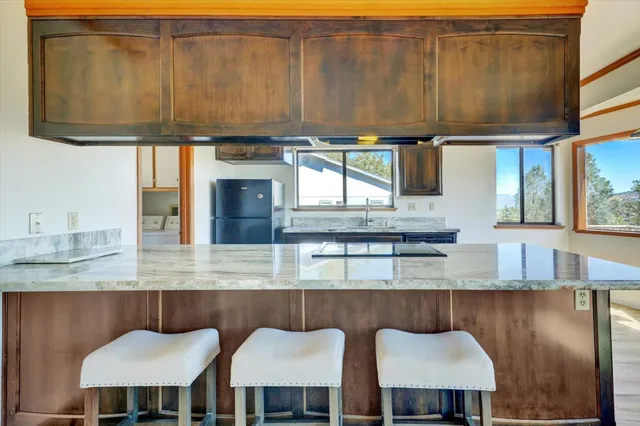 a kitchen with stainless steel appliances granite countertop a table chairs in it and wooden cabinets