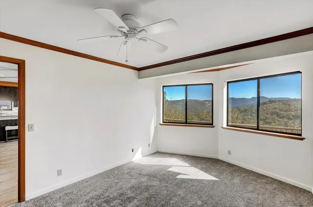 an empty room with windows and fan