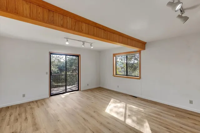 a view of an empty room with wooden floor and windows