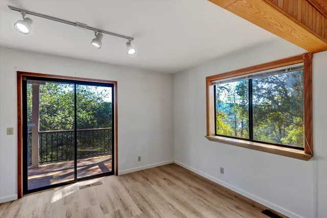 an empty room with wooden floor and windows