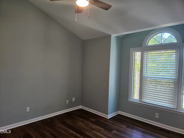 a view of an empty room with window and wooden floor